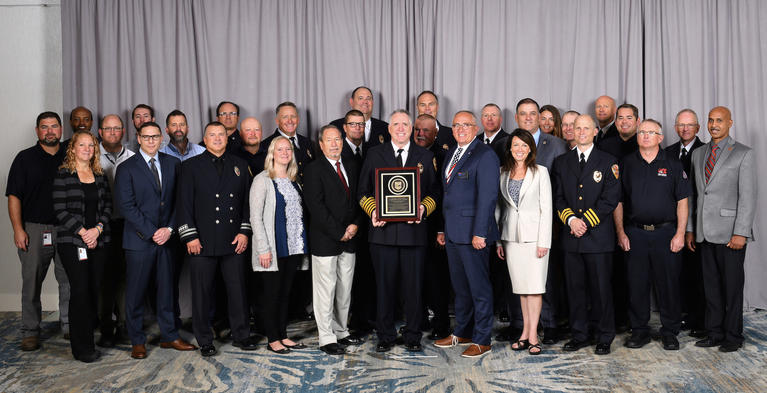 West Metro firefighters and staff in a group photo with accreditation plaque