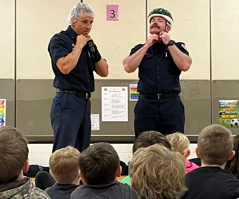firefighters teaching students to fit a helmet
