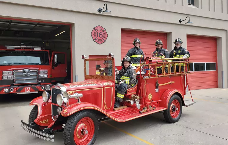 Image of firefighters in an old fashioned truck